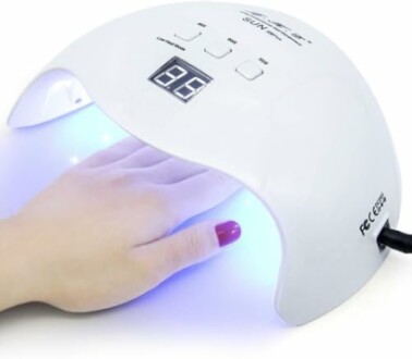 Hand under LED nail lamp for drying nails.